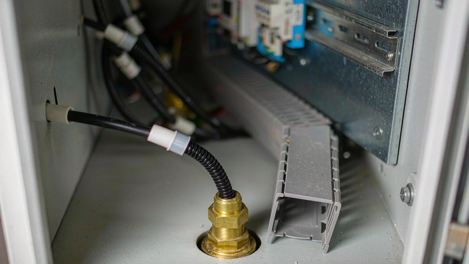 Control cable through a brass gland in a cabinet bottom plate with a wire duct close beneath