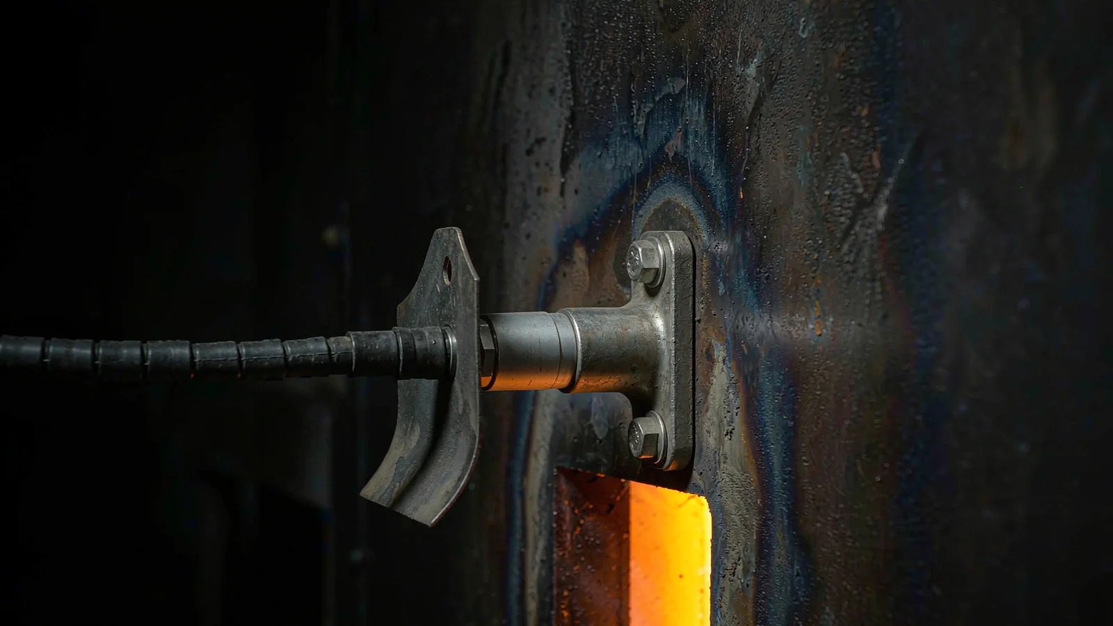 Stainless cable gland on a stand-off bracket away from a hot furnace wall with a heat shield behind