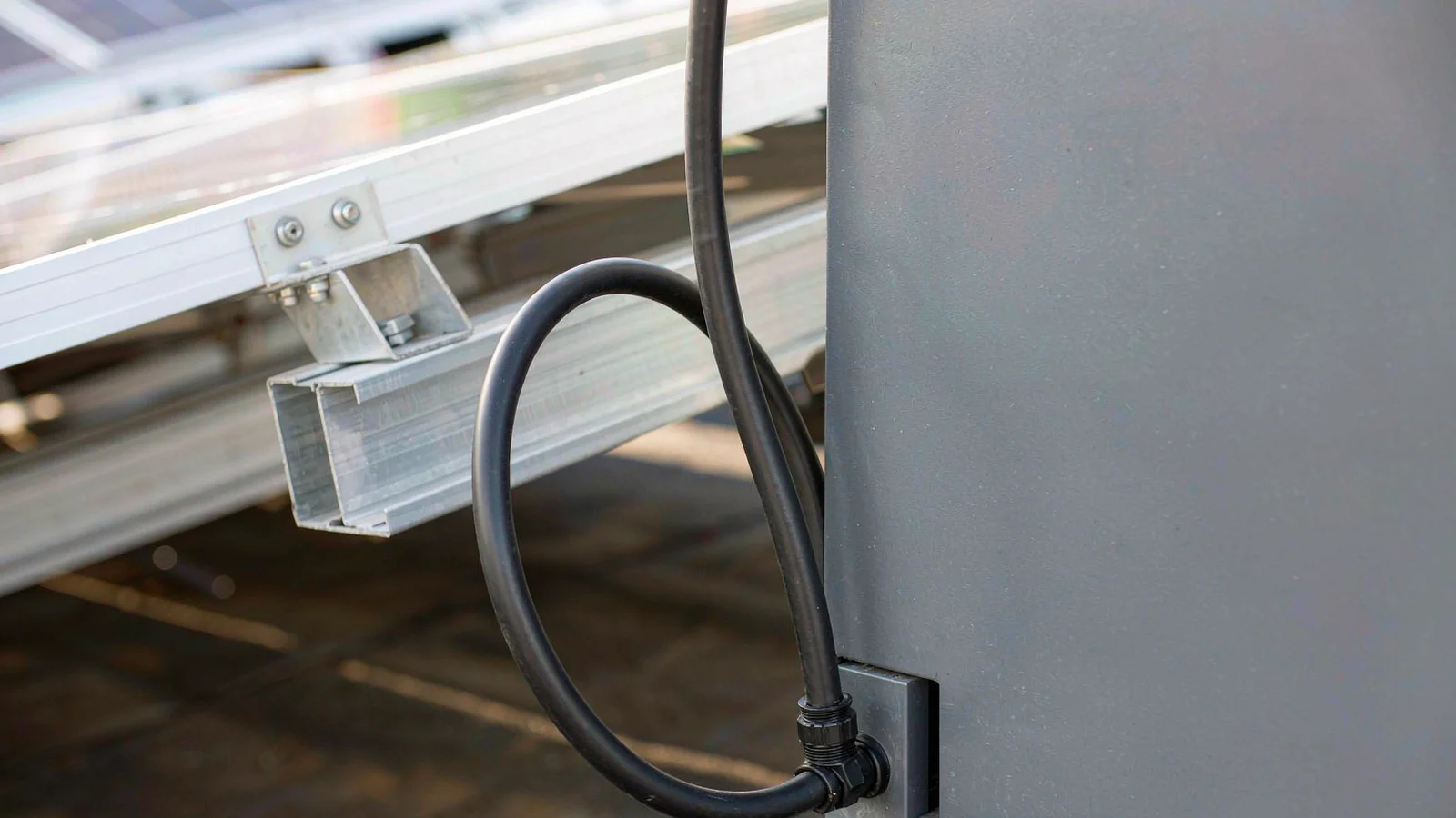 Solar cable forming a drip loop outside an enclosure before entering a cable gland on its bottom face