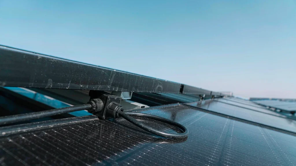 Black cable gland on a photovoltaic module junction box on a rooftop solar array